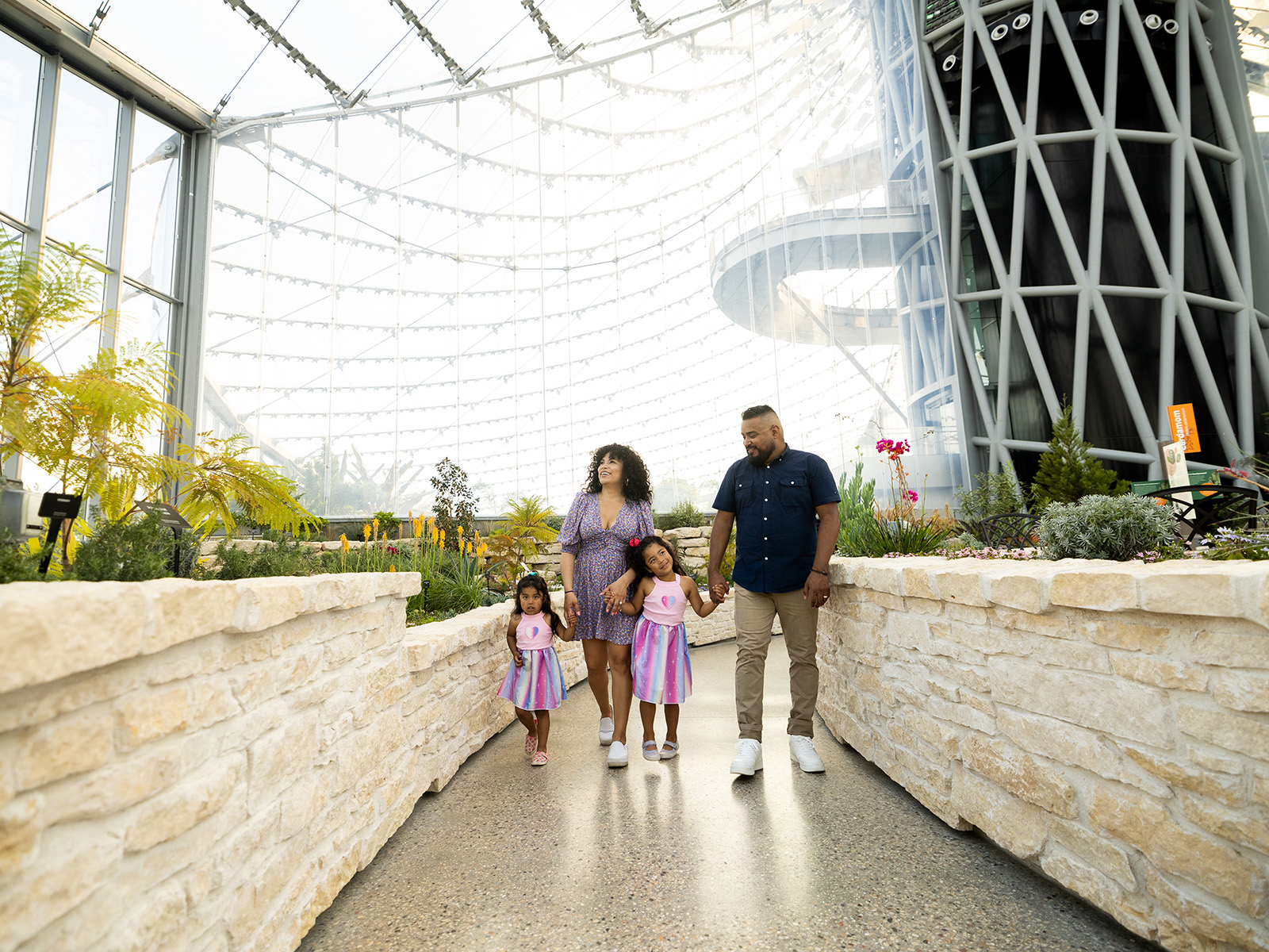 Mom, Dad, and two young kids walk along a pathway in the Mediterranean Biome